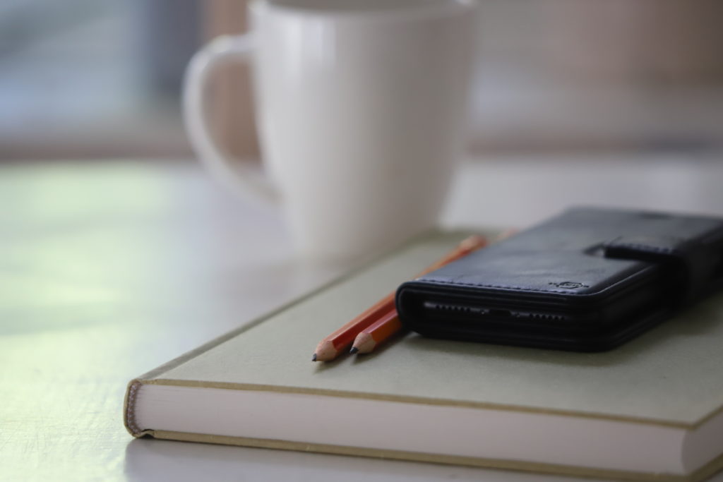 A smartphone, a notepad and a coffee cup