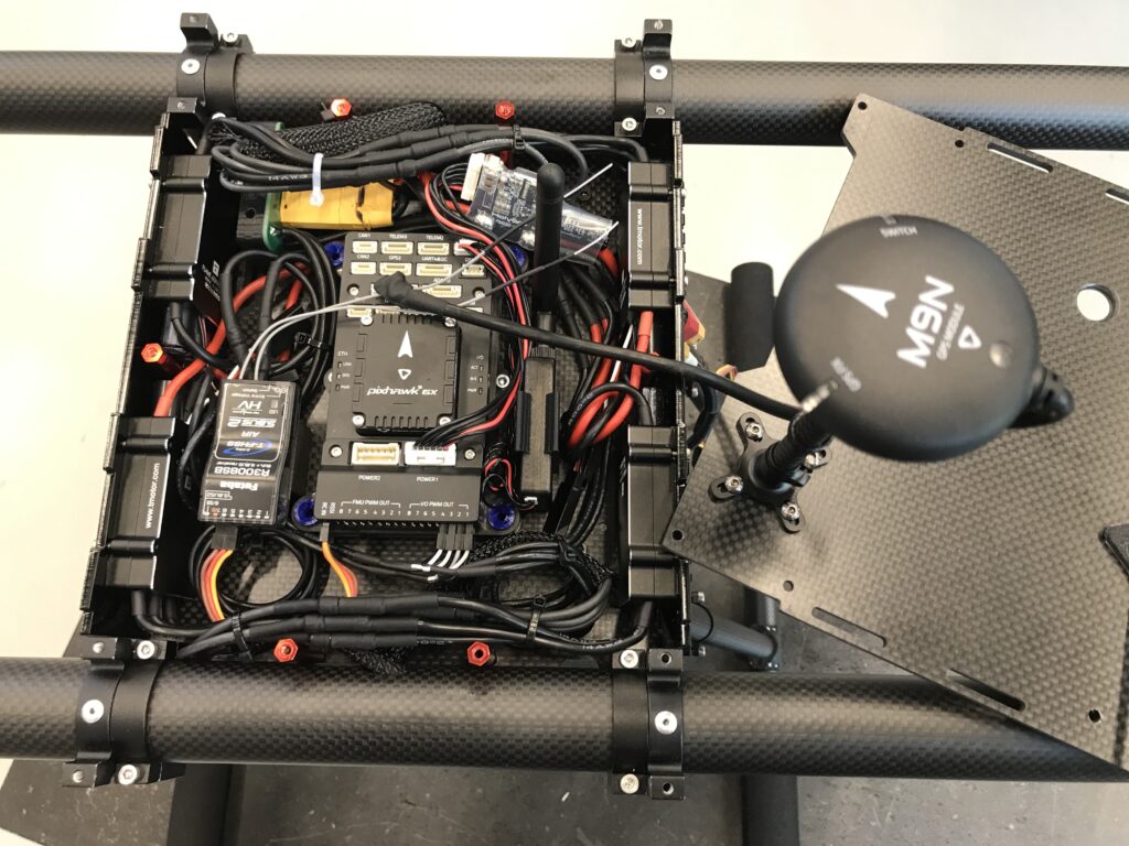 Lähikuvassa drone yläkansi irrottuna, josta näkyy rungon sisälle asennettua elektroniikkaa ja johtoja.
