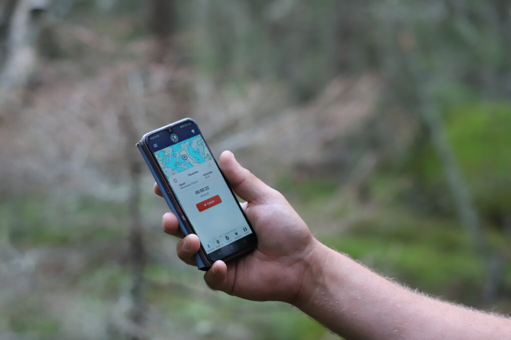 A hand with a mobile phone. There's an application open at the mobile phone, showing a map and a recording button.