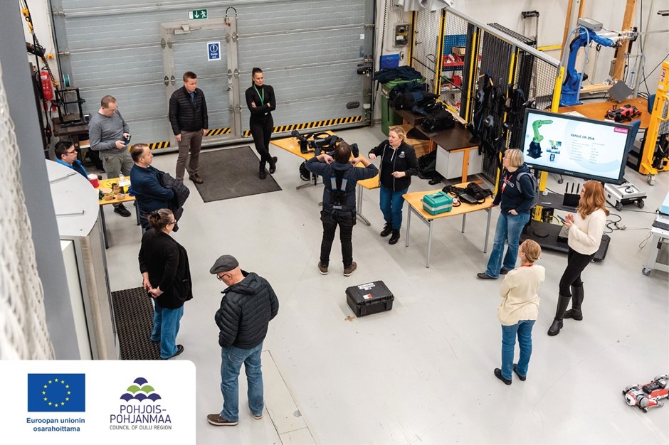 People in the Robotic laboratory, standing and looking at exoskeletons and robots.