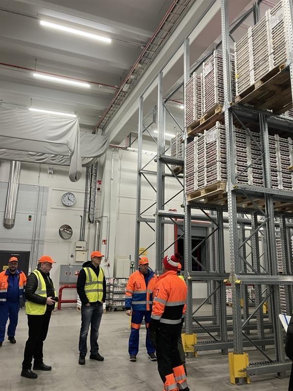 People standing and chatting in a large warehouse space.