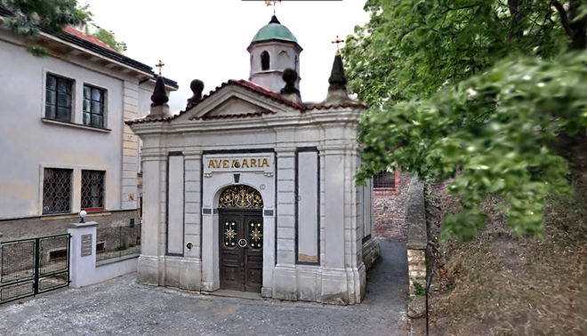 Historic chapel with an 'Ave Maria' inscription, framed by greenery.