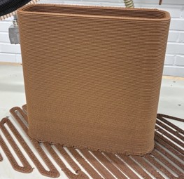 A 3D-printed box-shaped demonstrator surrounded by a printed raft produced during a robotic extrusion-based 3D-printing trial at Centria. 